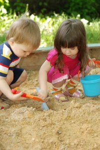 The boy and girl playing to a sandbox