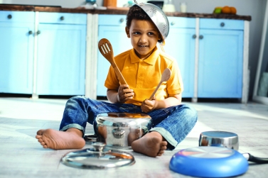 Joyful little boy playing on saucepan like a drummer